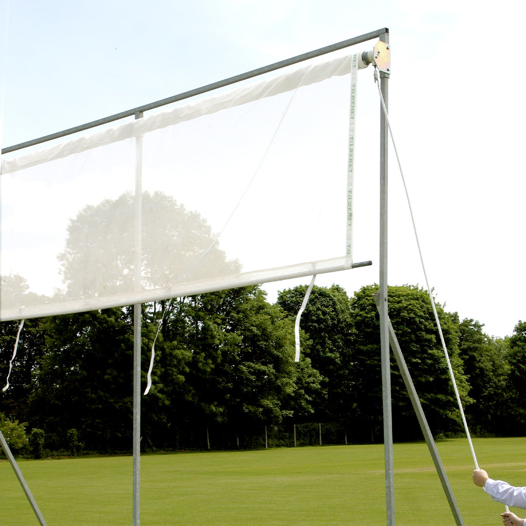white screen attached to frame in a field with trees in the background