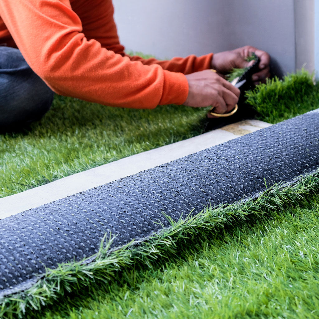 roll of grden turf being cut to size and installed
