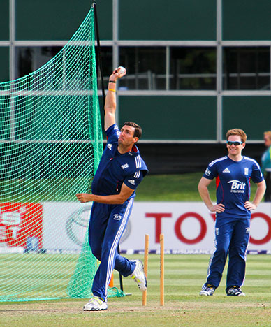 cricketer bowling with net in background