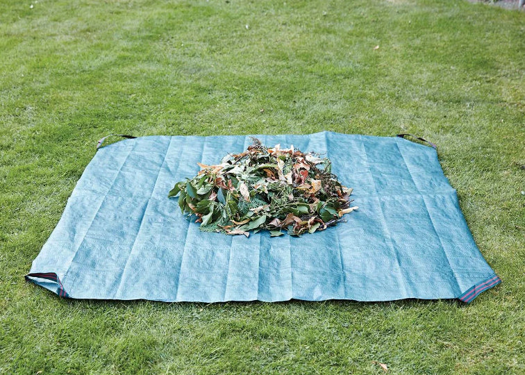 Blue garden wastetarpaulin sheet filled with leaves on a grassy surface