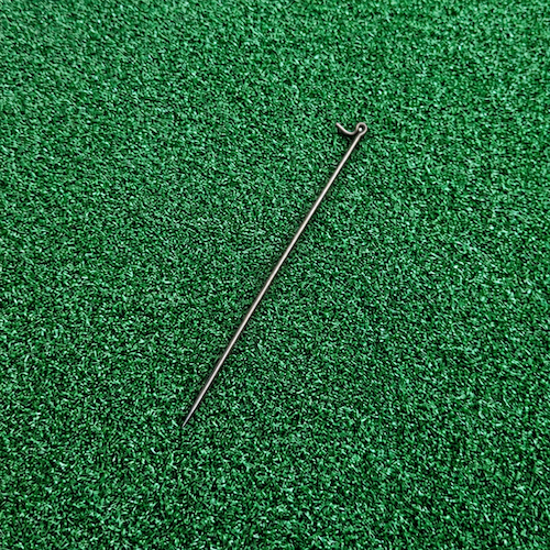 Metal fencing pin lying flat on green astroturf